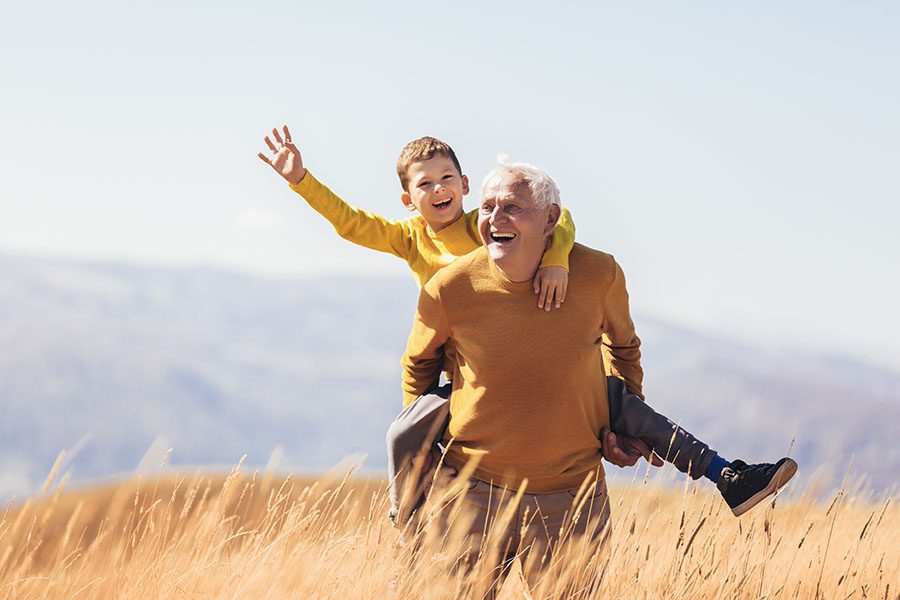 Contact - Happy Grandfather Giving His Grandson Piggyback Ride Outside