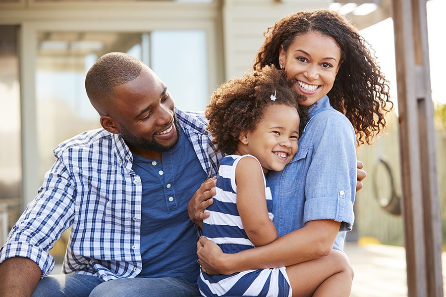 Personal Insurance - Portrait of Happy Parents Hugging Their Daughter Outside Their Home
